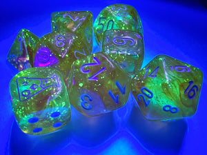 Borealis Luminary Canary polyhedral set, showing off brilliant sparkly yellow dice, glowing under a black light.