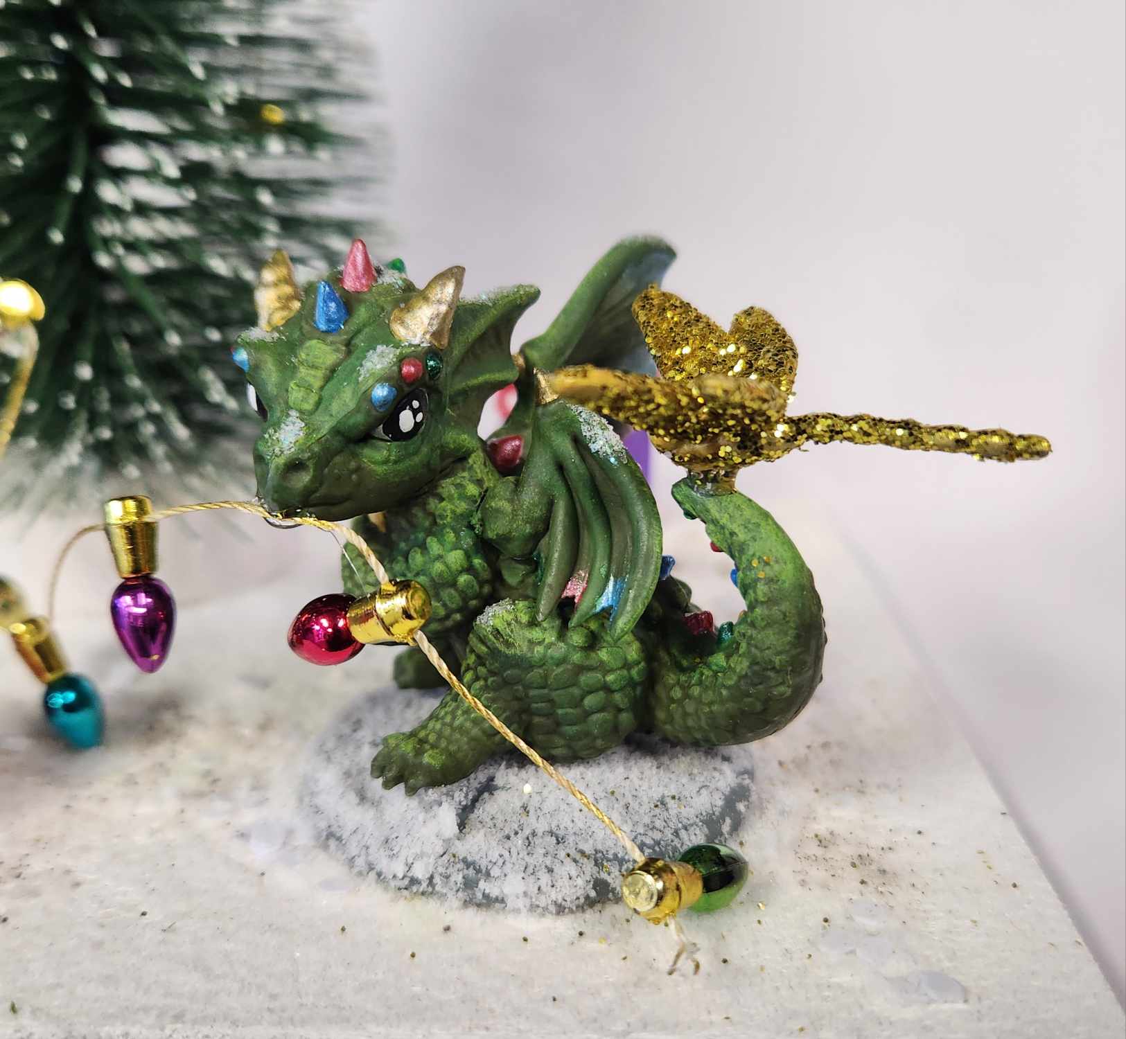 Small green dragon model on snow with Christmas lights
