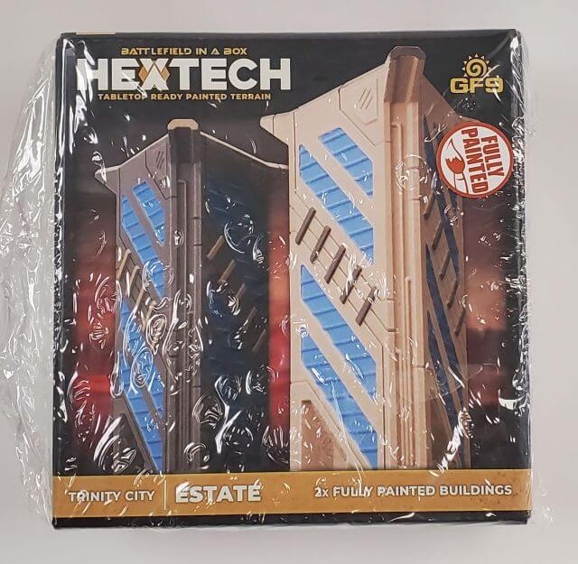 Packaged BattleTech Hextech Terrain set featuring two pre-painted buildings, labeled as 'Trinity City - Estate'.
