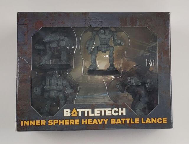 A product box for BattleTech: Inner Sphere Heavy Battle Lance featuring four BattleMechs, with the name of the product and the design of the mechs visible through a clear plastic window.