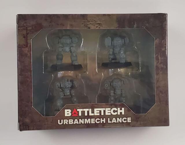 A product image of BattleTech UrbanMech Lance miniatures, showing four unpainted miniature figures in a clear plastic box with a BattleTech branding on the packaging.