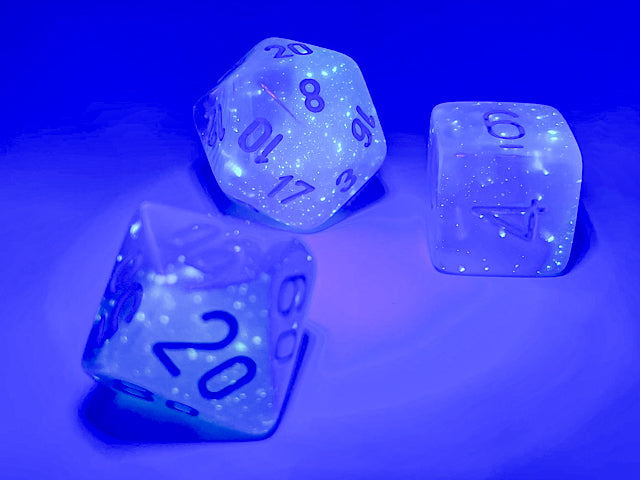 Examples of the Gemini Pearl Turquoise-White with blue 12mm dice sets under a blacklight to high light their luminescent features.