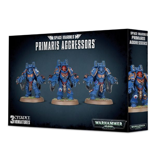 Packaging for Space Marines Primaris Aggressors miniature figures, showing three assembled marines in blue and black armor with ornate details, against a black background with the product name and Games Workshop branding.