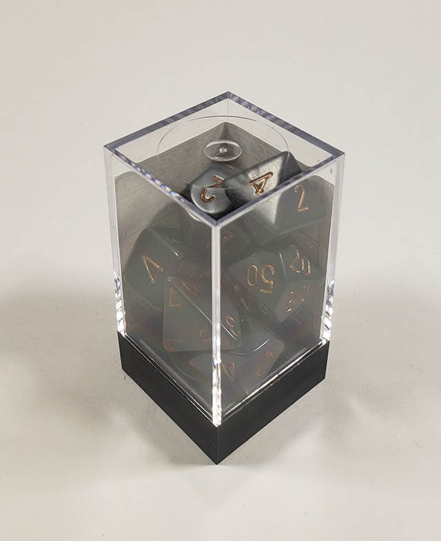 A close up of the Chessex Opaque Dark Grey with Copper polyhedral dice set in its package.