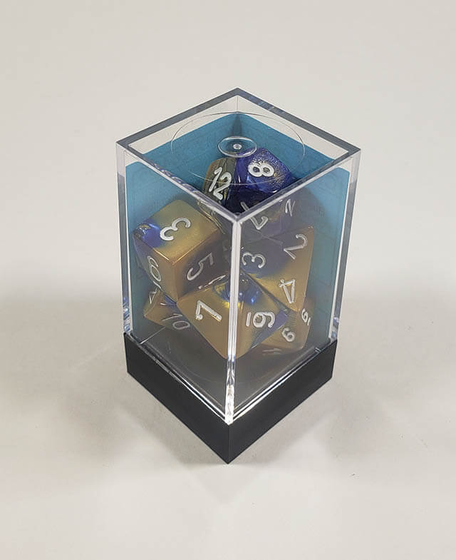 A close up of the Chessex Gemini blue and Gold polyhedral dice set in its package.