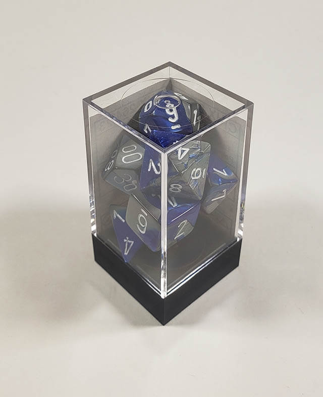 A close up of the Chessex Gemini Blue and Steel polyhedral dice set in its package.