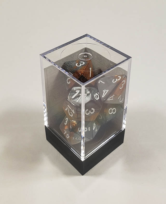 A close up of the Chessex Gemini Copper and Steel polyhedral dice set in its package.