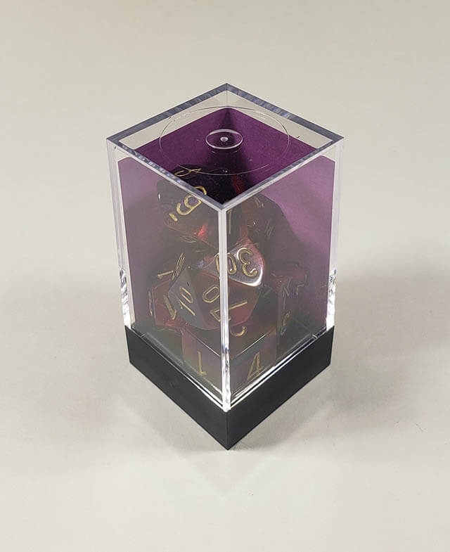 A close up of the Chessex Gemini Purple and Red polyhedral dice set in its package.