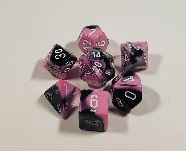 A close up of the Chessex Gemini Black and Pink polyhedral dice set.