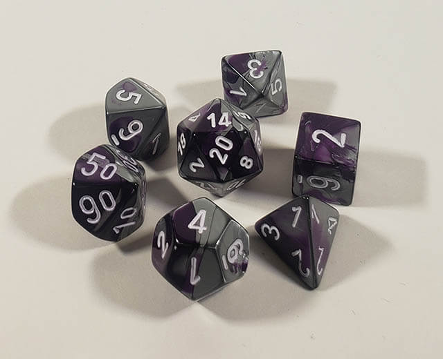 A close up of the Chessex Gemini Purple Steel polyhedral dice set.