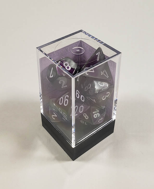 A close up of the Chessex Gemini Purple Steel polyhedral dice set in its package.