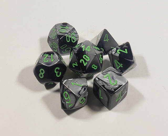 A close up of the Chessex Gemini Black and Grey polyhedral dice set.