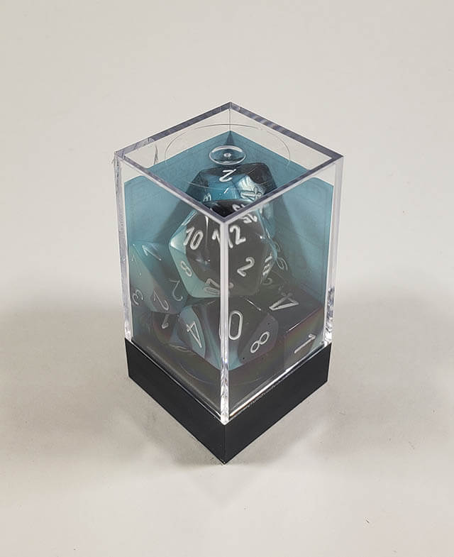 A close up of the Chessex Gemini Black and Shell polyhedral dice set in its package.