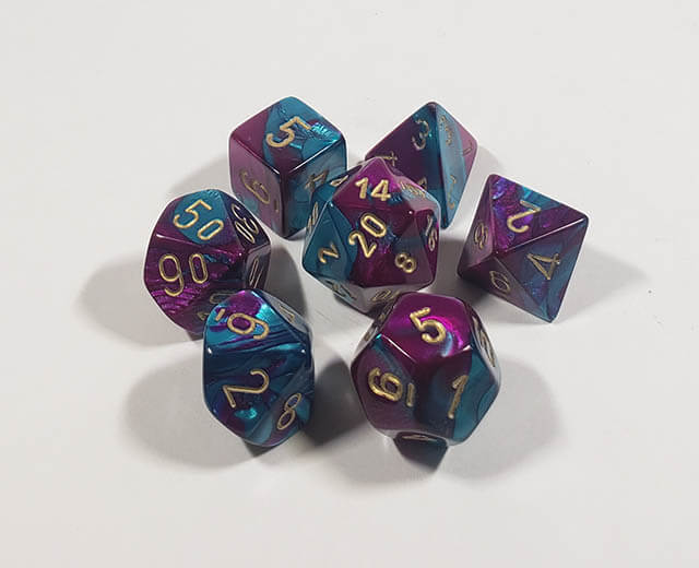 A close up of the Chessex Gemini Purple and Teal polyhedral dice set in its package.