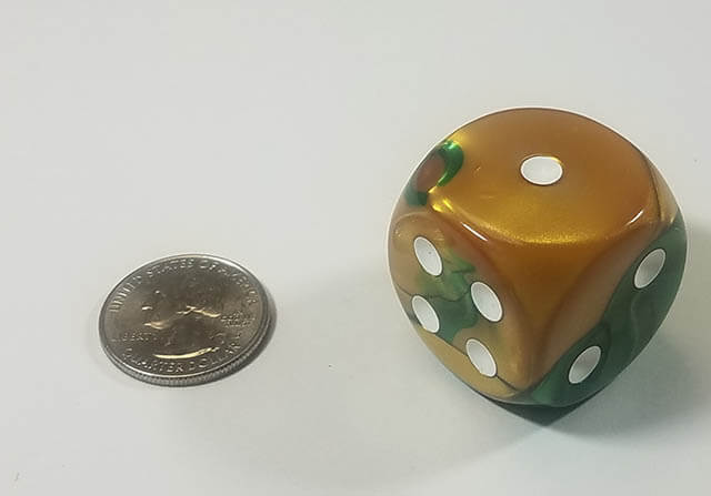 A 30mm six-sided dice with a blend of forest green, brilliant gold, and white colors, displayed next to a quarter for size comparison.
