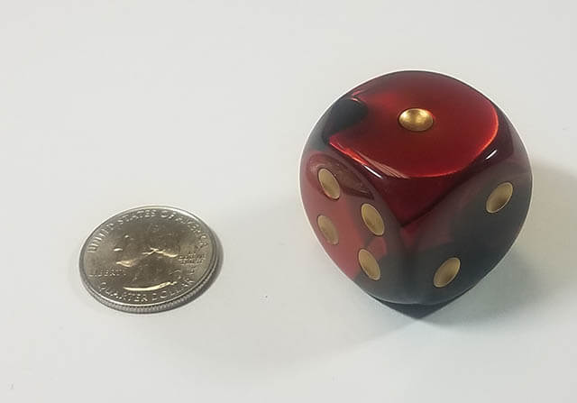 An example of the Chessex Gemini Black-Red with gold 30mm d6 with a quarter for scale.