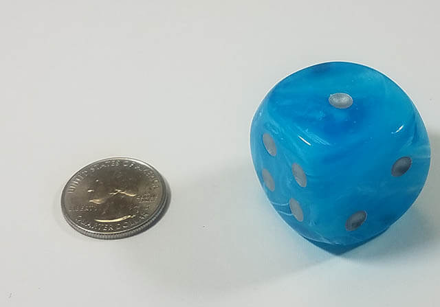An example of the Chessex Luminary Sky with Silver 30mm d6 with a quarter for scale.