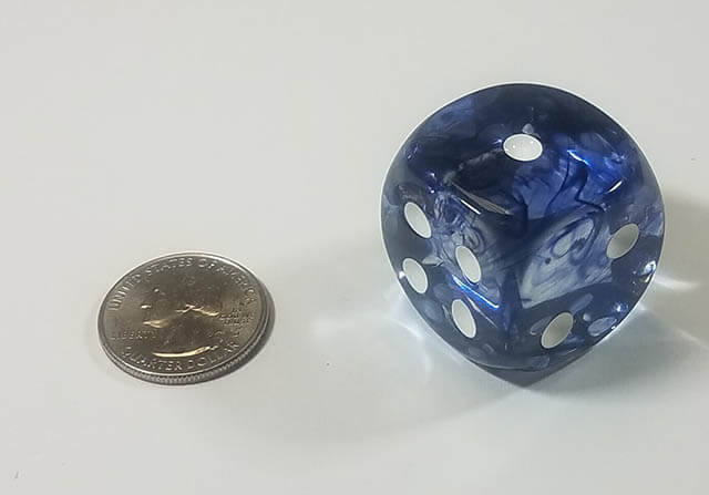 An example of the Chessex Nebula Black with white 30mm d6 with a quarter for scale.