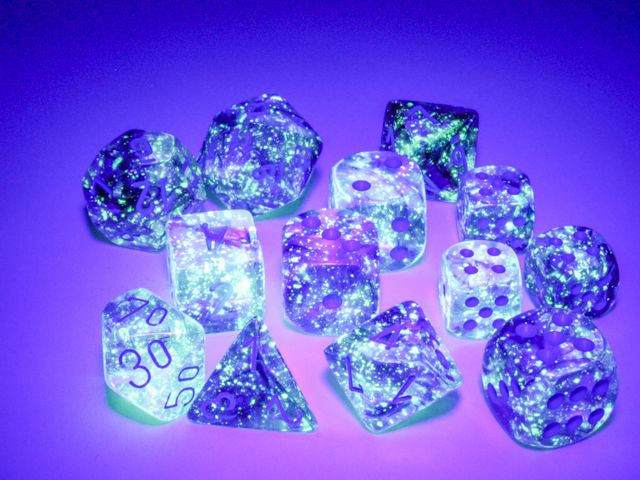 A close up of many of the dice from the Nebula Noctural with blue dice sets under black light.