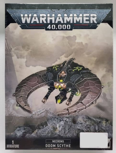 A Warhammer 40,000 Necron Doom Scythe miniature on a large oval base, with the miniature depicting a dark, robotic craft with a single figure standing atop.