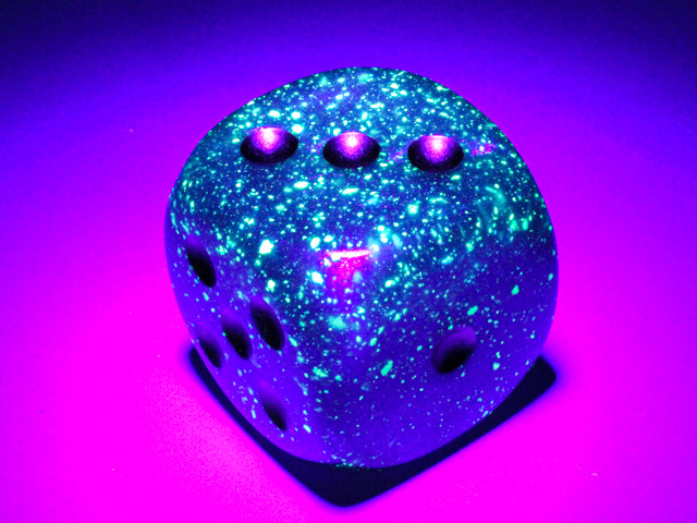 An example of the Chessex Borealis Luminary Royal Purple with Gold 30mm d6 under black light