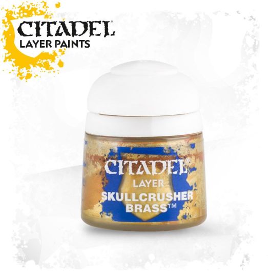 A pot of Citadel Layer paints in the color 'Skullcrusher Brass'. The pot is labeled and positioned against a white background with a splash of gold color at the top.