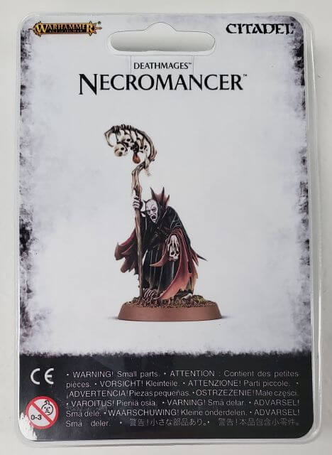 Packaged model kit of a Necromancer character, with components displayed on the base, labeled for Games Workshop's Warhammer fantasy game.