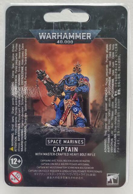 Packaging for Warhammer 40,000 Space Marines Captain with Master-Crafted Heavy Bolt Rifle, featuring an illustration of the character on a card with product information.