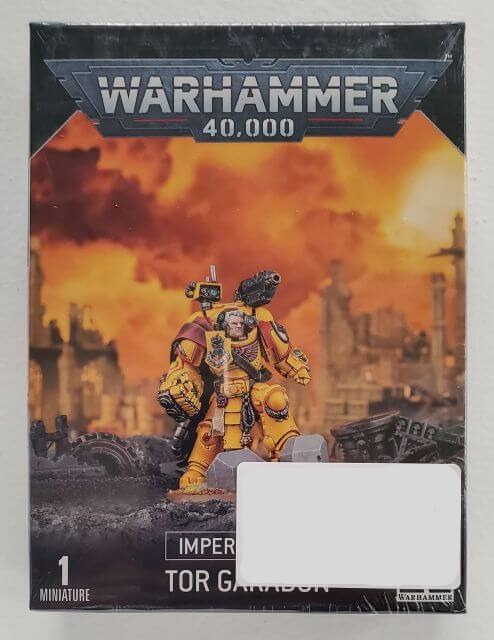 Packaging for Warhammer 40,000 Space Marines Imperial Fists Tor Garadon miniature set, featuring an illustration of a Space Marine captain on a round base with a backdrop of a cityscape under siege.