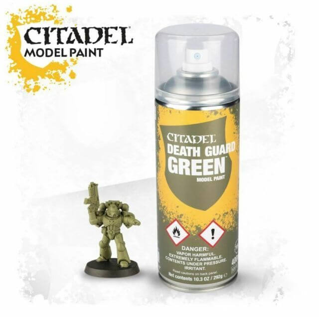 A can of Citadel model paint labeled 'DEATH GUARD GREEN' with a warning label, next to a miniature figure.