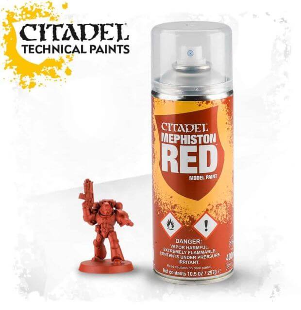 A can of Citadel Mephiston Red spray paint for model painting, alongside a miniature figurine.