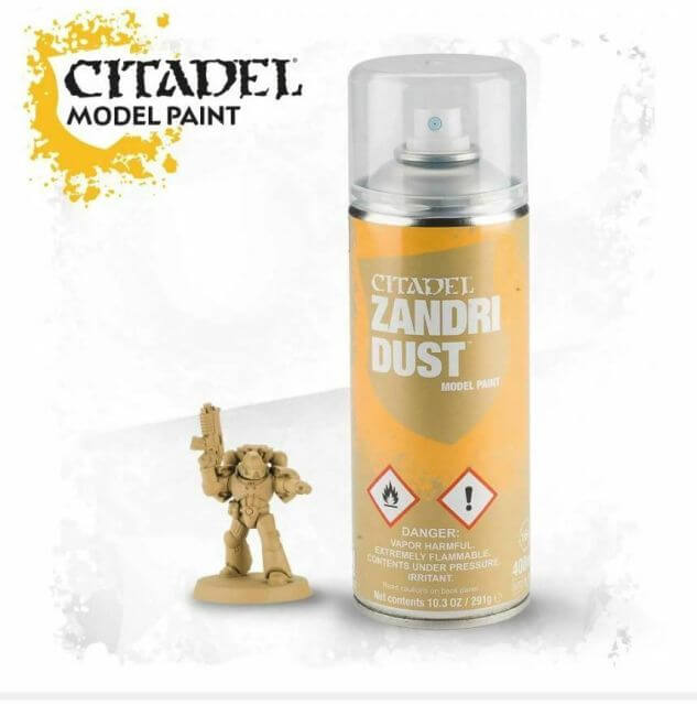 A can of Citadel model paint labeled 'Zandri Dust' alongside a miniature model figurine.