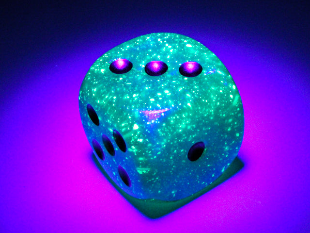 An example of the Chessex Borealis Teal with Gold 30mm d6 under blacklight.